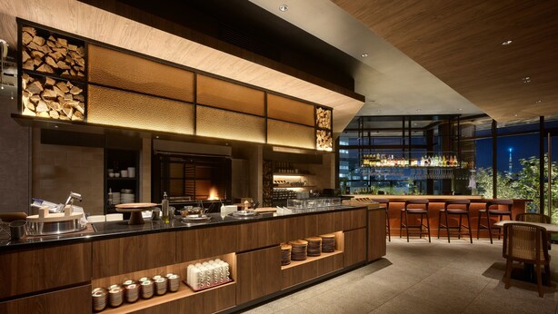 A modern bar area with a long counter, bar stools, and a view of the cityscape through large windows. - Mitsui Garden Hotel Ginza Tsukiji (Tokyo)