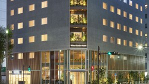 A modern hotel with a glass facade, multiple floors, and a green-lit entrance. - Mitsui Garden Hotel Ginza Tsukiji (Tokyo)