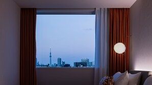A hotel room with a large window, a bed, and a city skyline view. - Mitsui Garden Hotel Ginza Tsukiji (Tokyo)