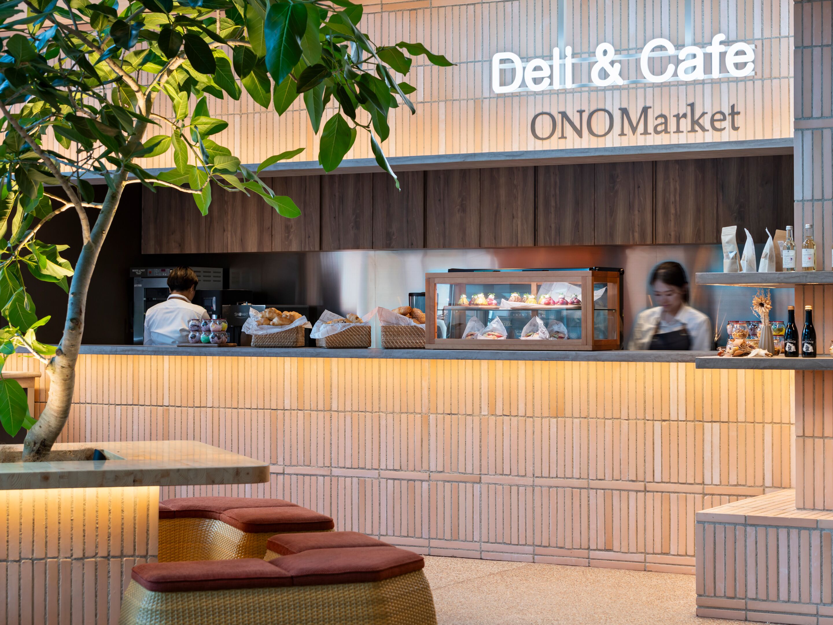 A DELL & Cafe at ONOMarket with a counter displaying pastries and a blurred background of a person.