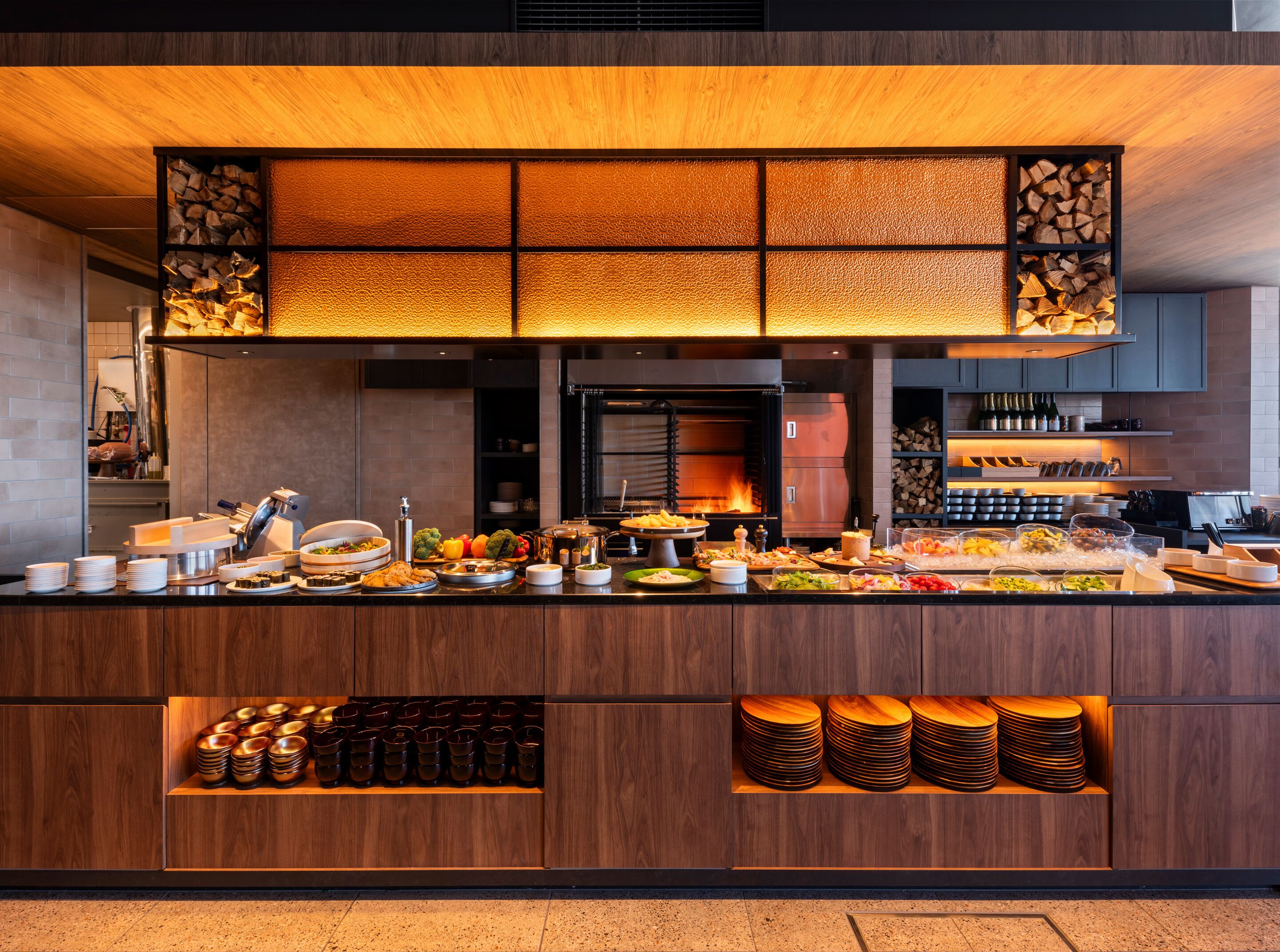 A buffet setup with various food items and beverages, a wood-burning stove, and neatly arranged dishes.