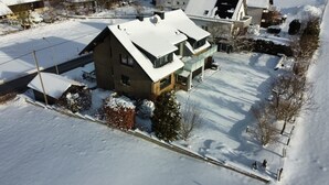 A two-story house with a snow-covered roof and yard. - Apartment 'Wiesenblick' with Balcony and Wi-Fi (Brilon)
