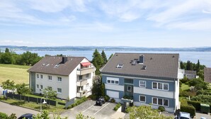 A residential area with two multi-story buildings, a parking lot, and a view of a body of water. - Holiday Apartment 'Bodenseeblick' with Lake View, Balcony and Wi-Fi (Konstanz)