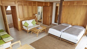 A room with a bed, a sofa, a table, and wooden paneling. - Holiday Apartment 'Bodenseeblick' with Lake View, Balcony and Wi-Fi (Konstanz)