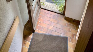 A door leading to a garden with a lawn, flowers, and a metal grate. - Holiday Apartment 'Bodenseeblick' with Lake View, Balcony and Wi-Fi (Konstanz)