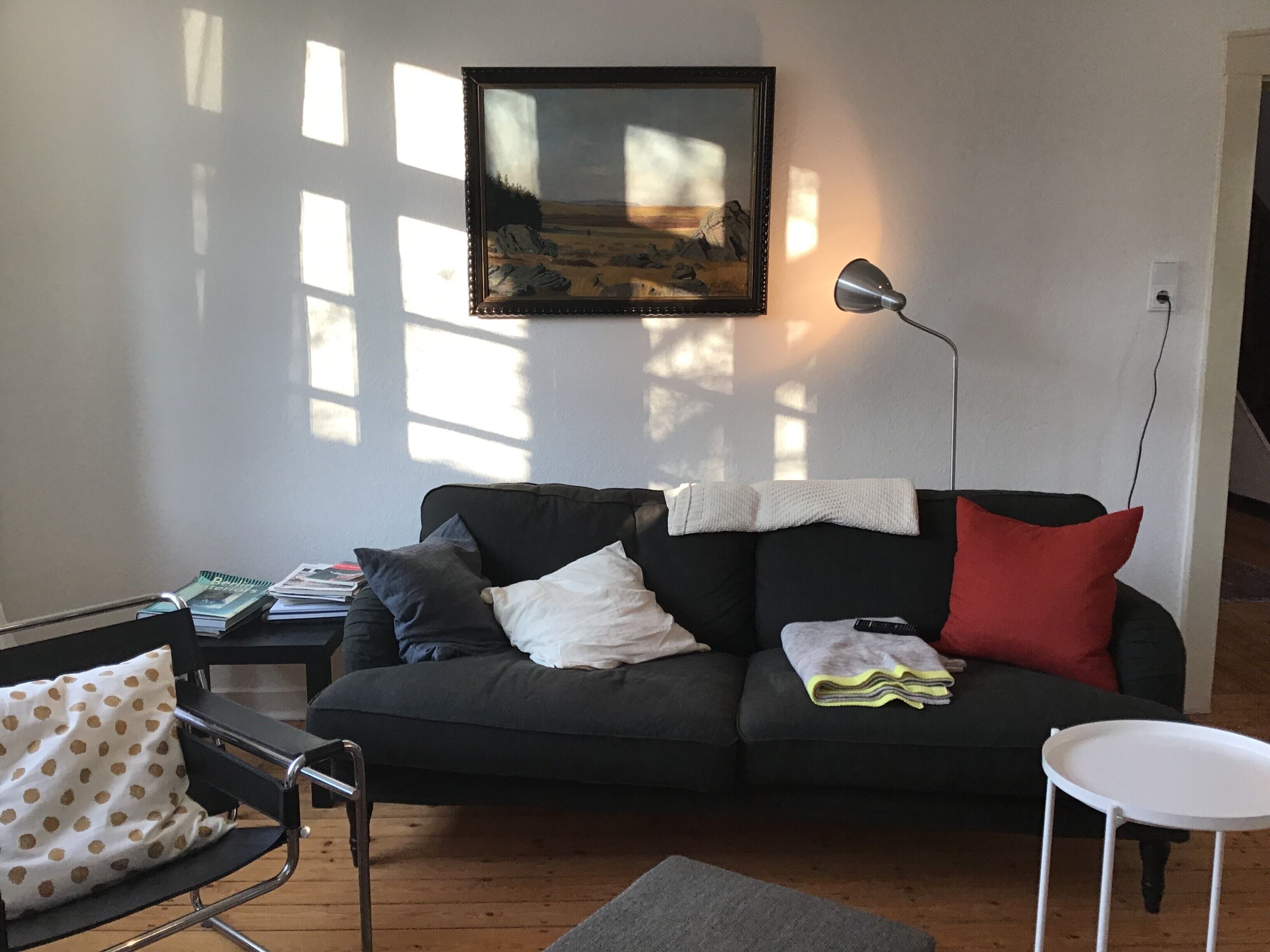 A living room with a sofa, a side table, a lamp, and a framed picture on the wall.