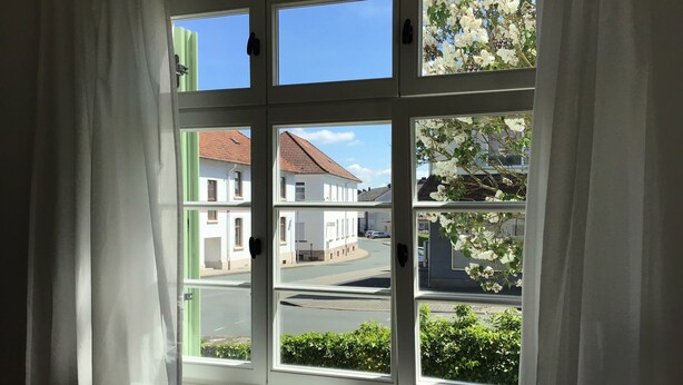 Una ventana con varios cristales, vista a edificios y cielo despejado.