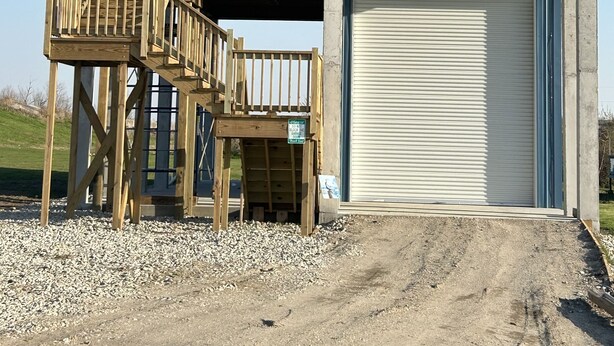 Een gebouw met twee verdiepingen, een houten terras en een garage.