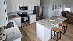 Een moderne keuken met witte kasten, roestvrijstalen apparatuur en een granieten aanrecht.