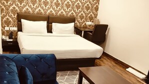 Um quarto com uma cama, um sofá azul, uma mesa de centro de madeira, uma parede estampada e um ventilador de teto.