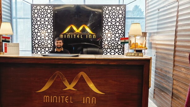Uma mesa de recepção com um logotipo, um certificado emoldurado e um aviso com o horário de check-out.