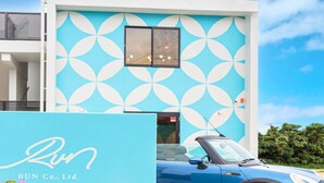 A modern building with a blue and white geometric pattern on the facade, a blue car parked in front, and a sign with "RUN Co., Ltd."
