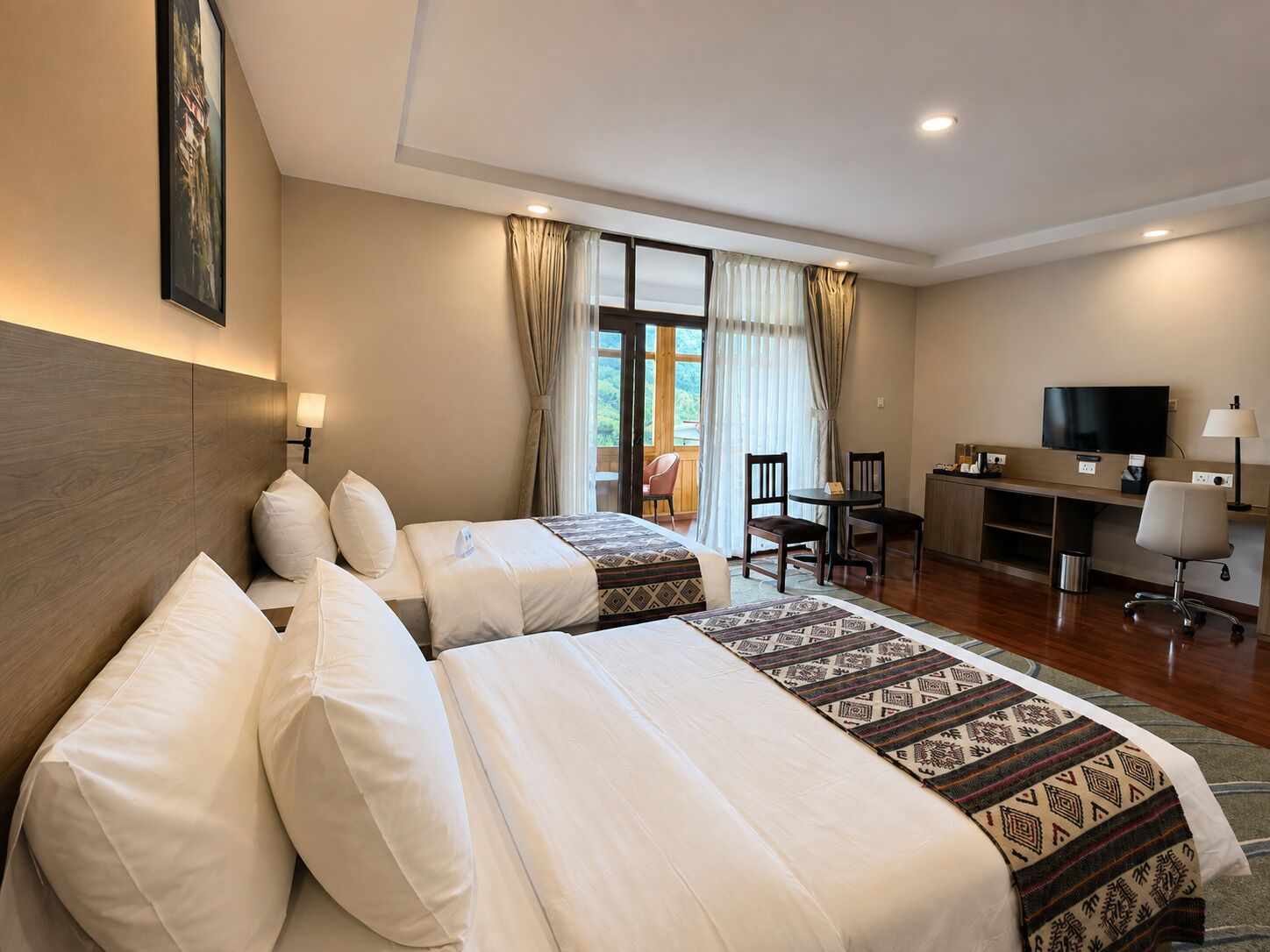 Habitación de hotel con dos camas, un escritorio, una silla, un televisor y una ventana con cortinas.
