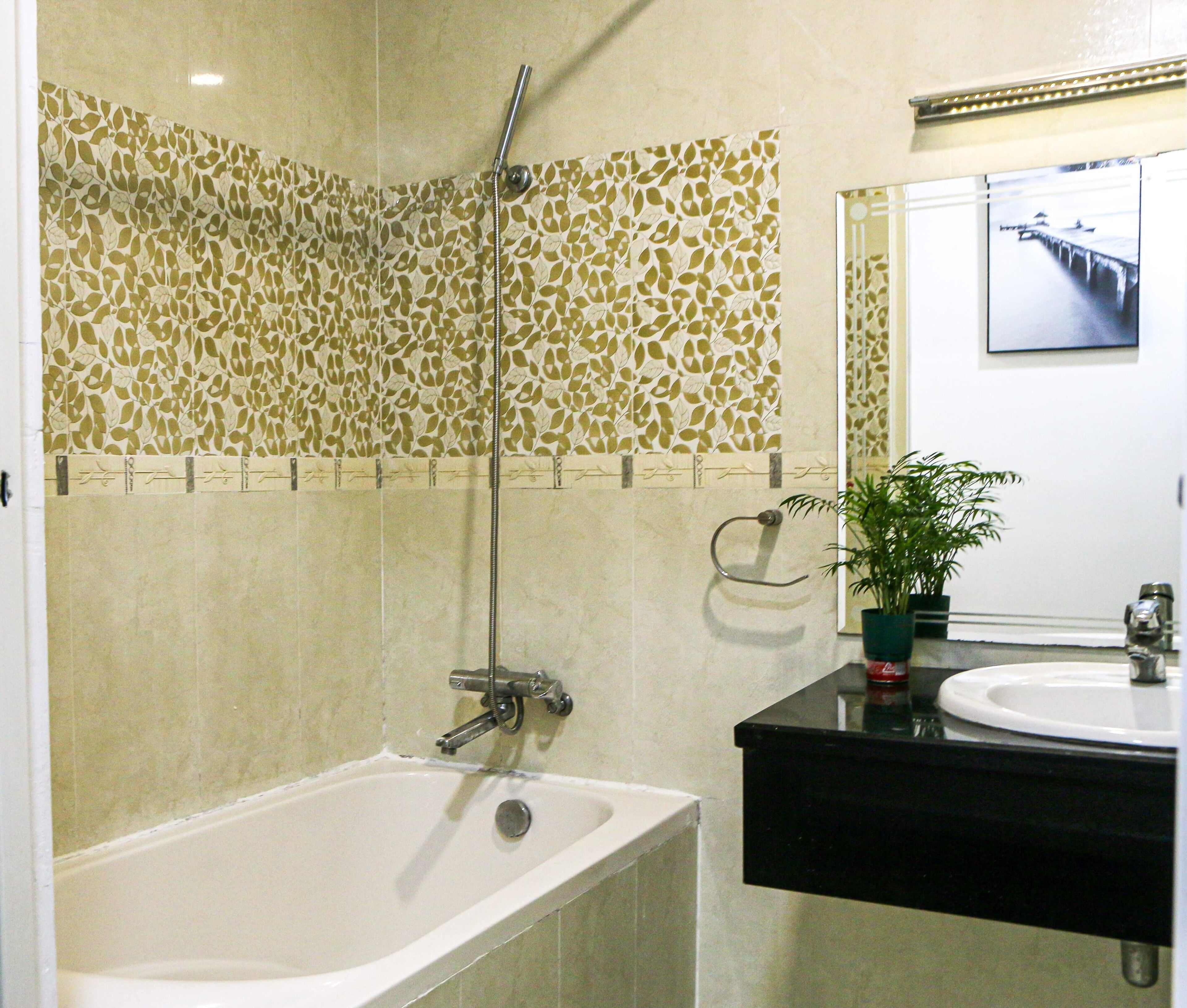 A bathroom with a bathtub, a shower, a sink, and a mirror.