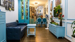 A room with a blue sofa, a small table, a blue cabinet, and a dining area with two chairs and a table. - FH Homestay (Ho Chi Minh City)