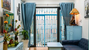 A room with a blue sofa, a small table, a cabinet, and a potted plant. - FH Homestay (Ho Chi Minh City)
