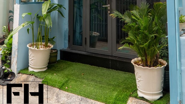 A blue building with a sign reading "FH Homestay" and multiple hanging flower pots. - FH Homestay (Ho Chi Minh City)