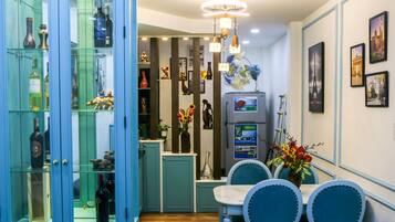 A dining area with a table and chairs, a refrigerator, and a display cabinet with bottles.