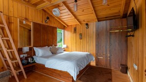 Ein Schlafzimmer einer Holzhütte mit Bett, Leiter und montiertem Fernseher.