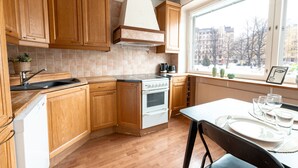 Una cocina con armarios de madera, una estufa blanca y una ventana con vista a edificios.