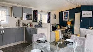 A compact living space with a kitchenette, dining area, and seating. - The Hideout (New Quay)