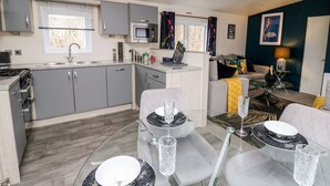 A compact living space with a kitchenette, dining area, and a living room. - The Hideout (New Quay)