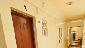 A hallway with a wooden door labeled '3', a yellow floor, and a doormat with vegetables. - Lux Suites Geanna Suites Nanyuki (Nanyuki)