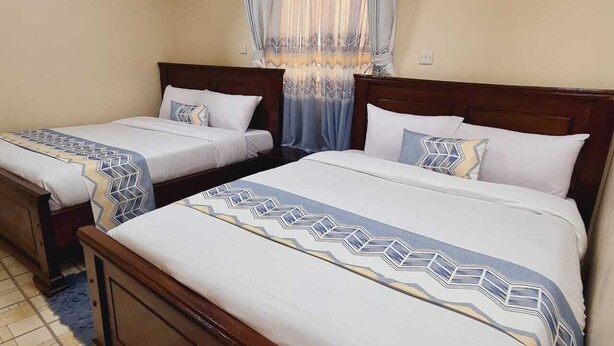 A hotel room with two single beds and a larger bed, all with matching headboards and bedding. - Lux Suites Geanna Suites Nanyuki (Nanyuki)