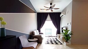 Een moderne woonkamer met een bank, een klein rond tafeltje, een plafondventilator en een groot raam met gordijnen.