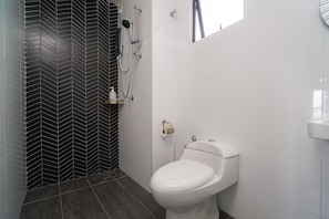 Een badkamer met een zwart-wit betegelde muur, een wit toilet en een douchegedeelte.