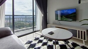 Een moderne woonkamer met een groot raam, een flatscreen televisie, een ronde salontafel en een bank.