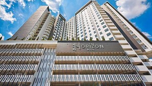 Een modern hoog hotel met een opvallend bord met daarop 'The Horizon', met een gevel in rasterpatroon en meerdere balkons.