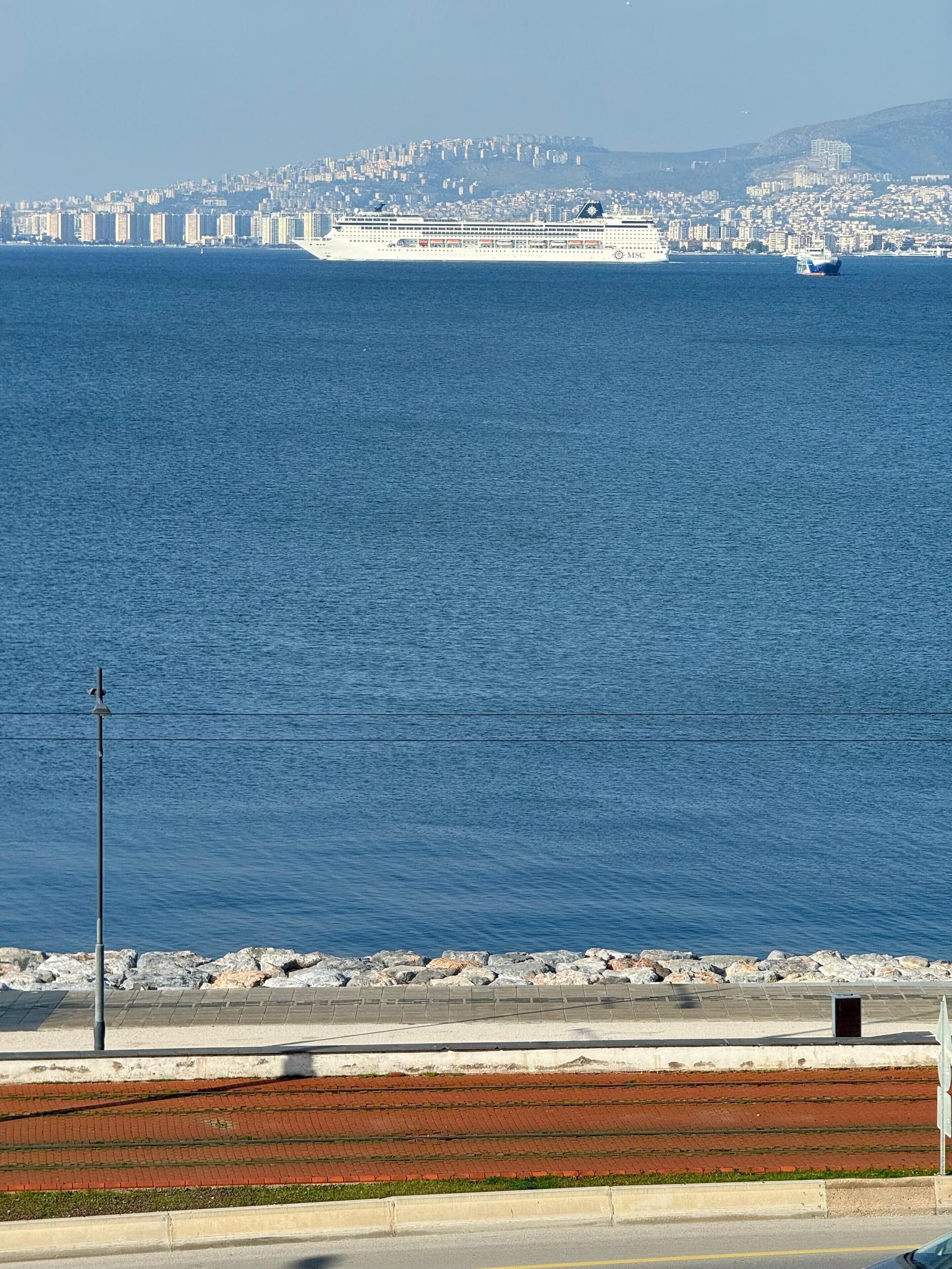 Un paisaje urbano costero con un gran barco crucero atracado en el puerto.