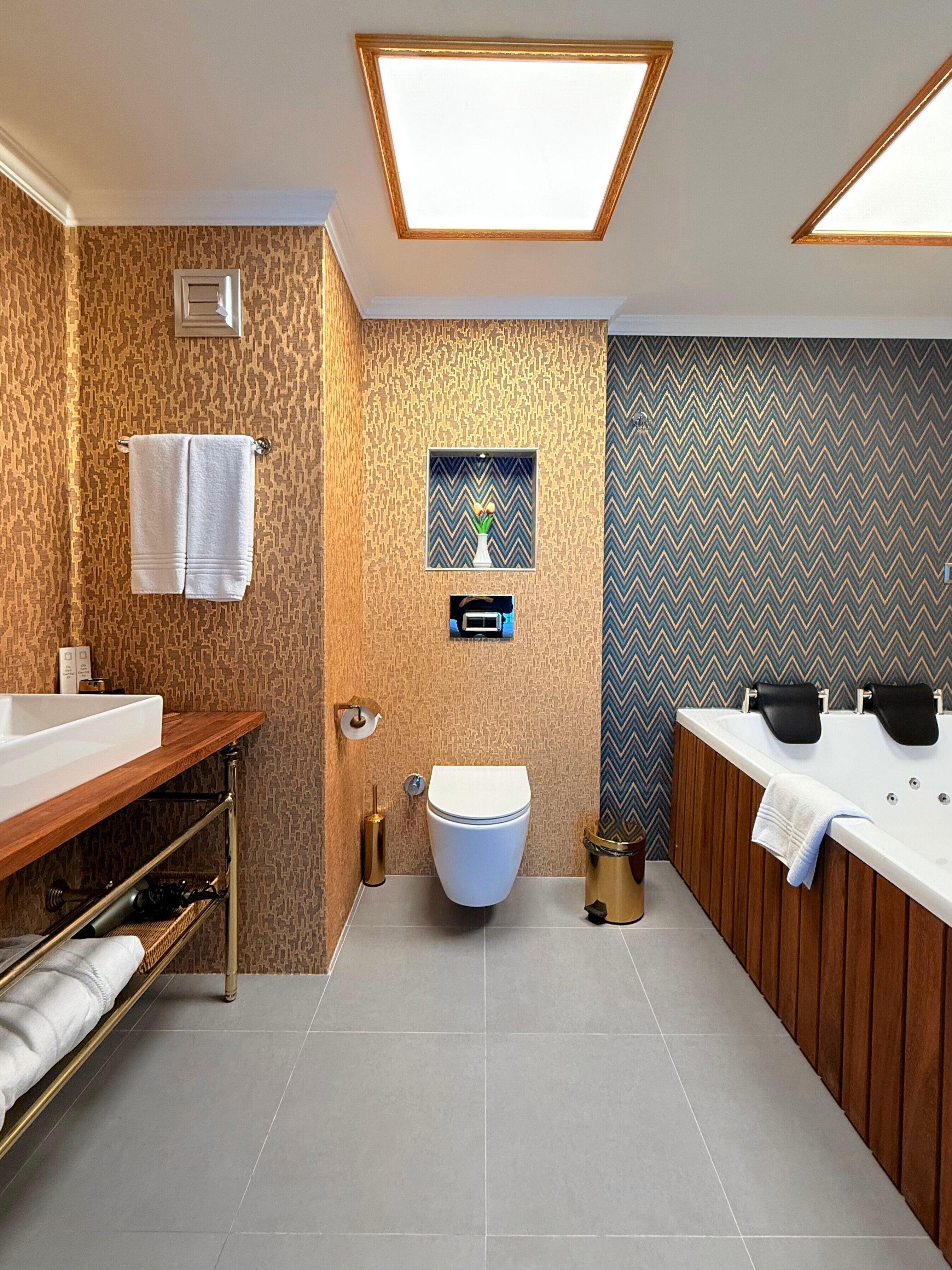 A modern bathroom with a wooden vanity, a white toilet, and a large bathtub.