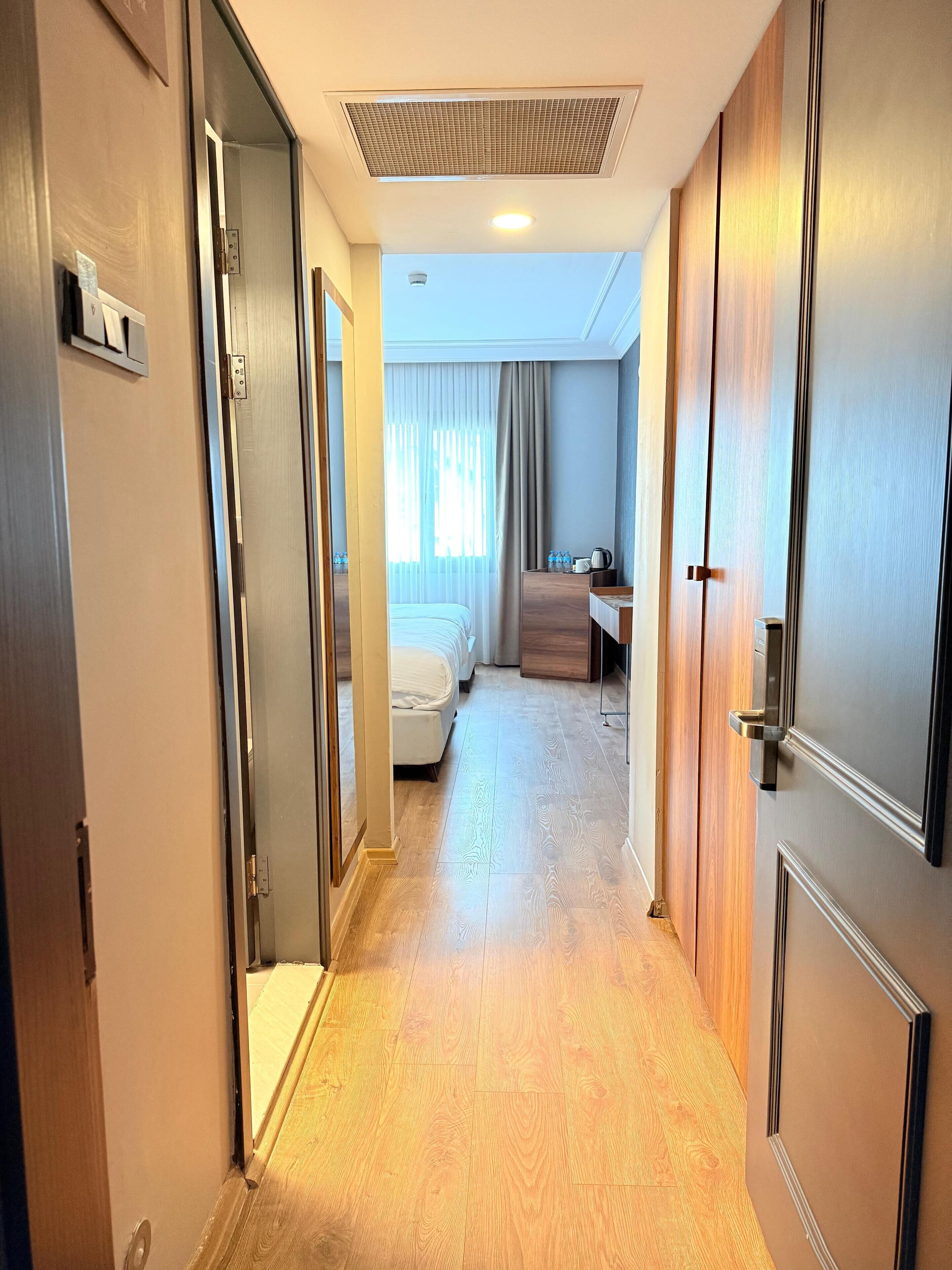 A hotel corridor with a bed, a desk, and a bathroom.