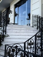 A staircase with ornate black metal railings and white walls.