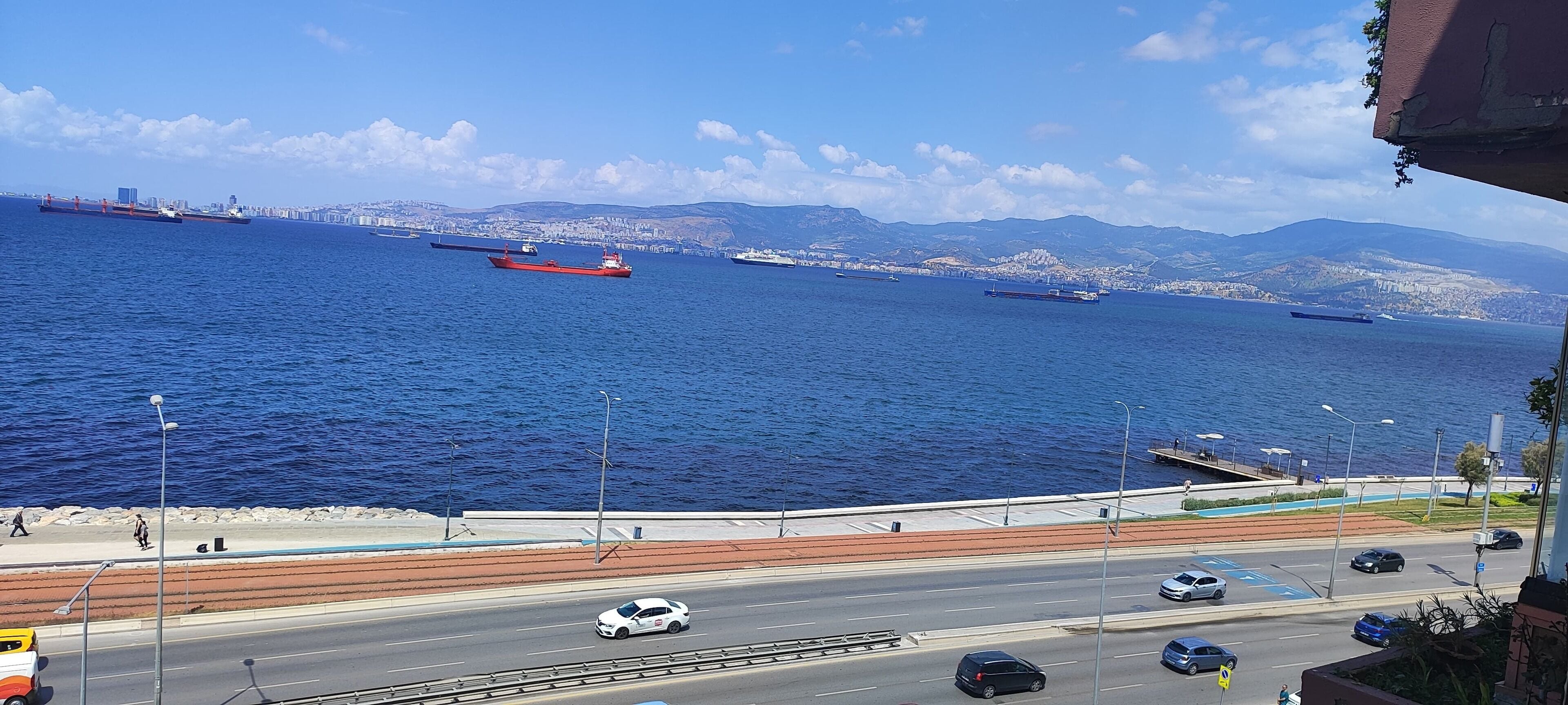 Una carretera costera con vistas al mar y un horizonte urbano distante.
