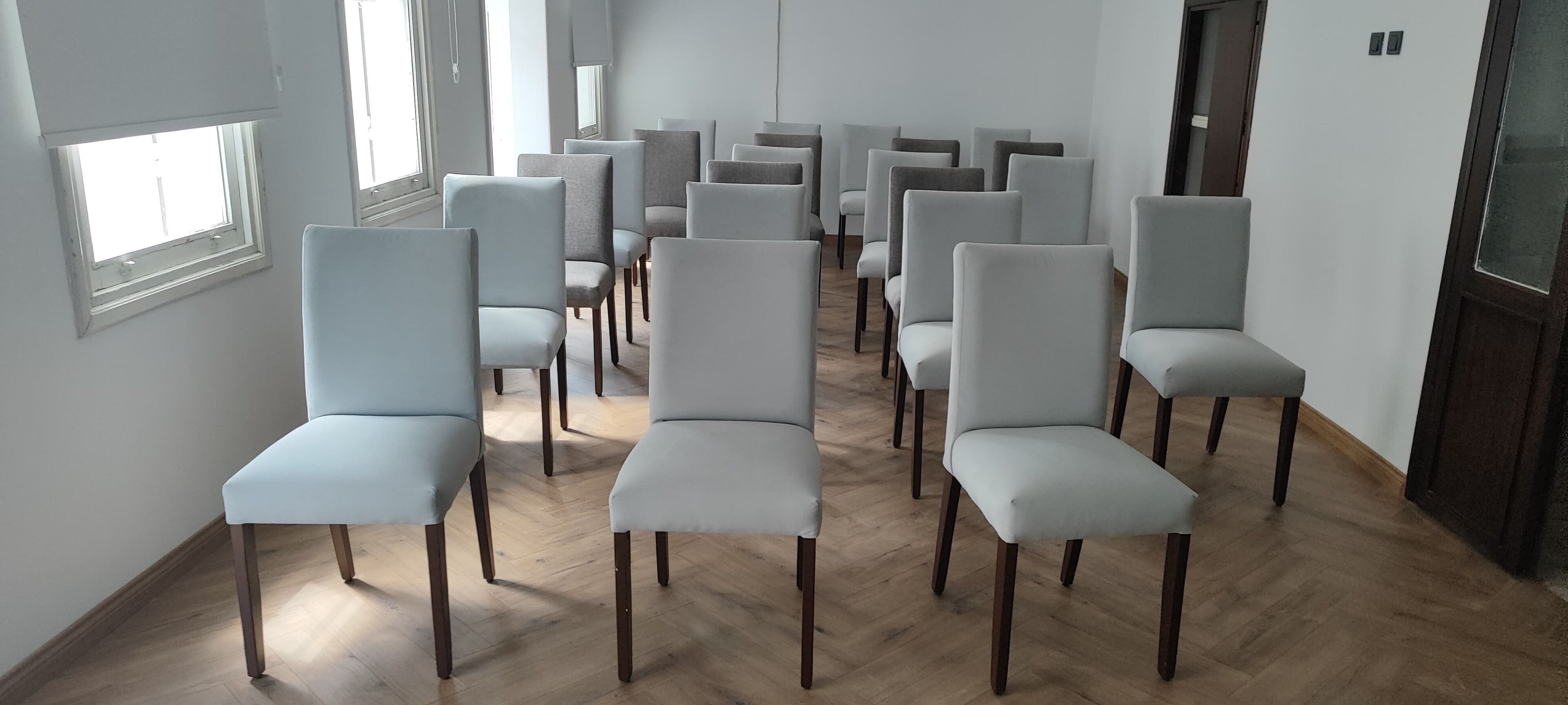 Een kamer met rijen lichtgrijze gestoffeerde stoelen, klaar om plaats te nemen.