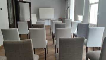 A conference room with rows of chairs facing a whiteboard, large windows, and a wooden floor.
