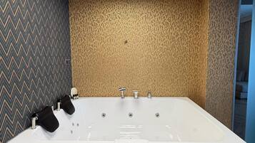 A modern bathroom with a freestanding bathtub, a wooden vanity, and a patterned wall.