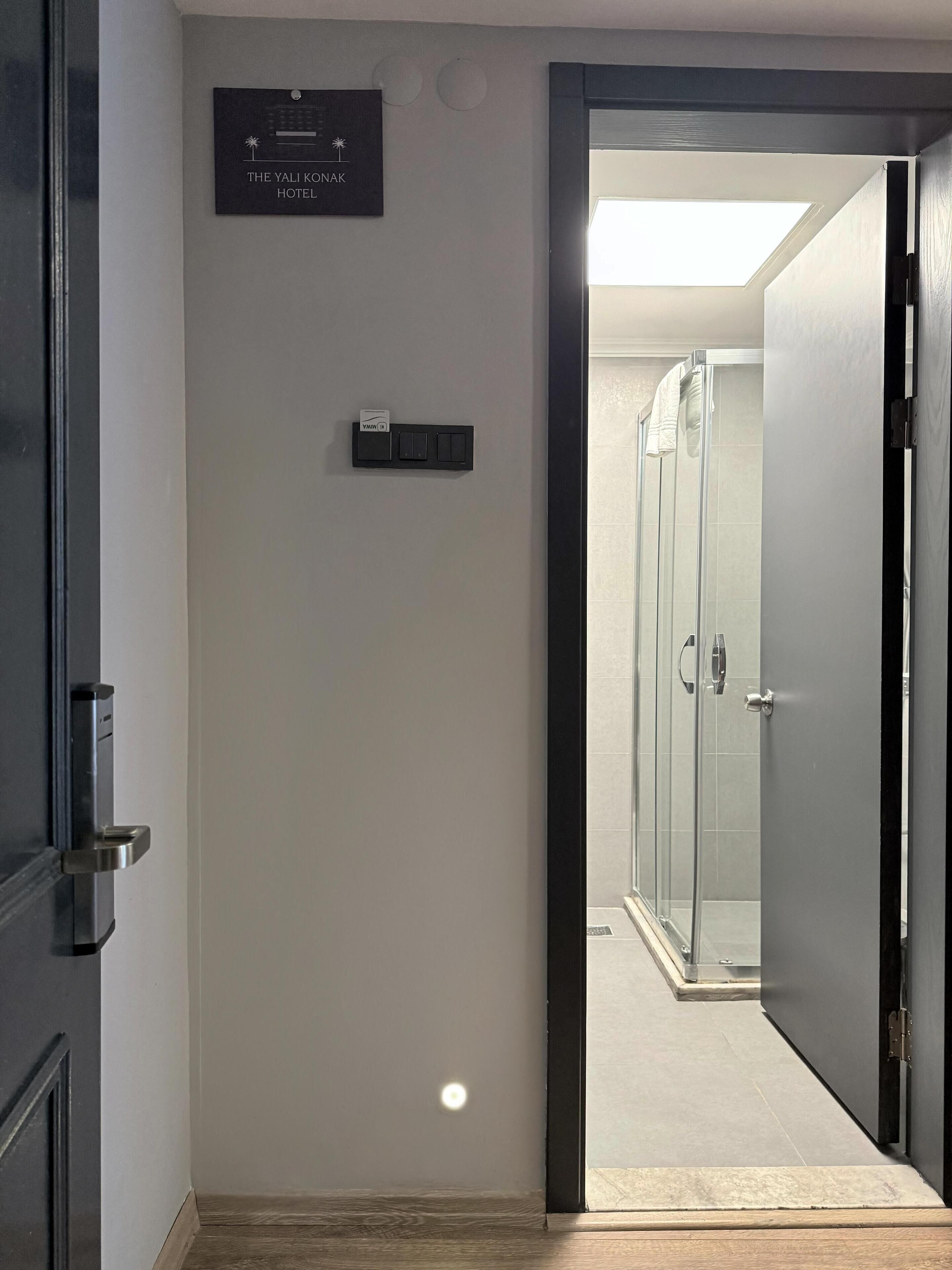 Een hotelgang met een bordje voor 'The Yali Konak Hotel' en een lichtschakelaar aan de muur.