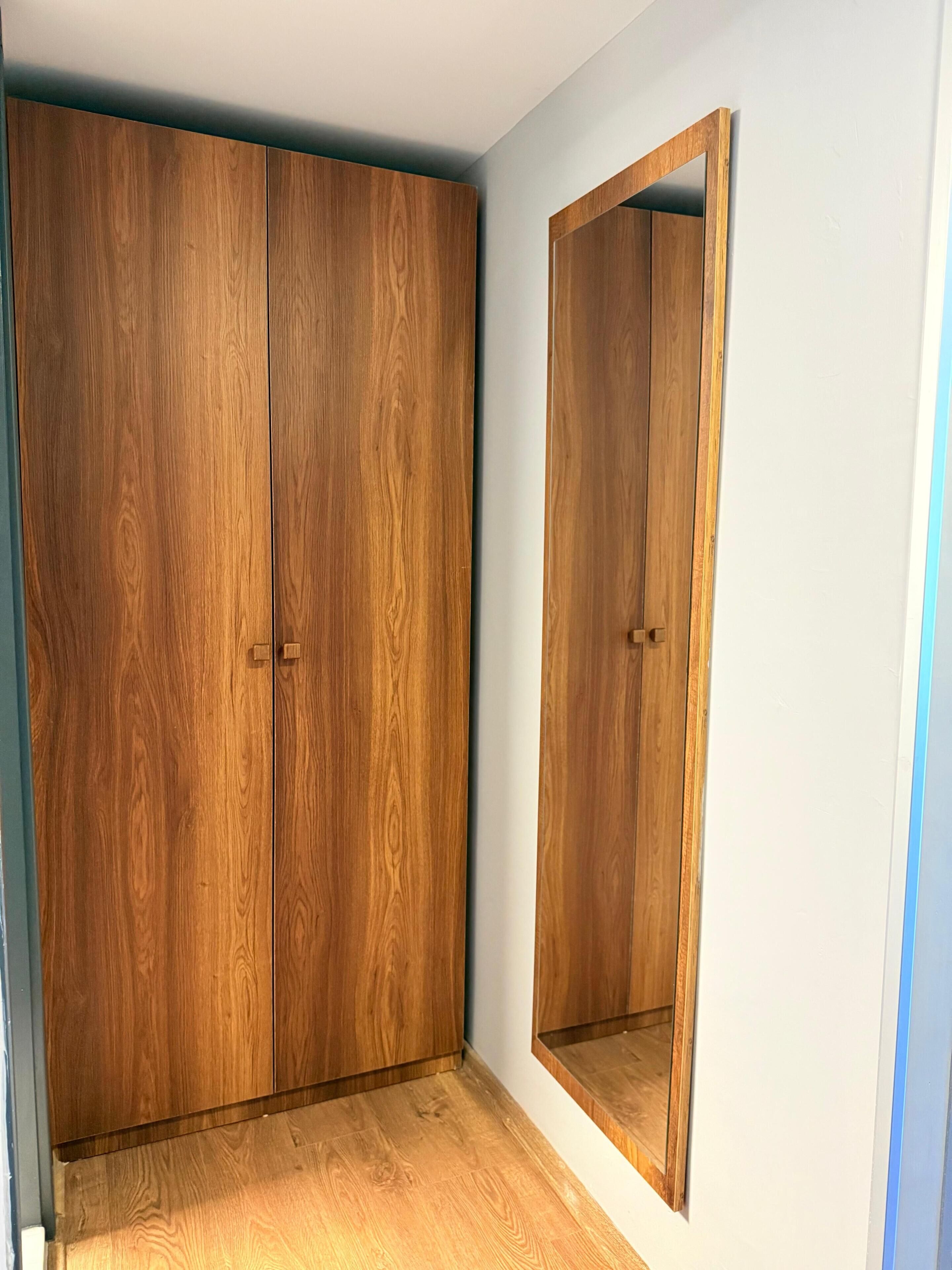 Una habitación con un armario de madera y un espejo.