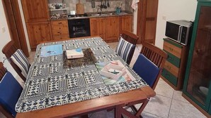 A dining area with a large table, wooden cabinets, and a microwave. - Summer vacations in Villasimius in a beautiful villa with garden (Sardegna)