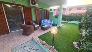 A patio with wicker furniture, a small table, and a lamp post. - Summer vacations in Villasimius in a beautiful villa with garden (Sardegna)