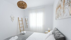 A neatly made bed with a gray quilt, white linens, and rolled towels. A woven light fixture hangs above. - Casa Sunrise - Rooftop, 5 Swimming Pools and Panoramic Sea view @ Peñon de Ifach (Calp)