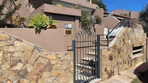 Un bâtiment moderne doté d’un mur en pierre, d’un portail en métal et d’un escalier menant à un balcon.