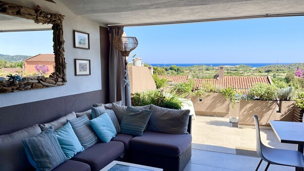 Un balcon avec un canapé, une table et une vue sur la mer et les bâtiments environnants.