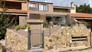 Une maison moderne à deux étages, dotée d’une façade en pierre, d’une entrée sécurisée et d’un petit jardin.