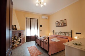Un dormitorio con cama, chimenea, un cuadro en la pared y una mesita de noche.