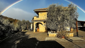 A building with an archway, surrounded by trees and a paved area.